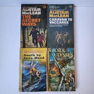 Puede incluir: Cuatro libros de bolsillo vintage de Alistair MacLean. Los títulos incluyen "The Secret Ways", "Caravan to Vaccares", "South by Java Head" y "H.M.S. Ulysses". Las portadas presentan ilustraciones de escenas de acción y texto.