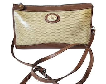 May include: A rectangular Dooney & Bourke crossbody bag with a woven beige center and brown leather trim. The bag features a long, adjustable strap and a small, oval logo on the front.