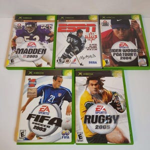 May include: Five Xbox video game cases. The games are: EA Sports Madden NFL 2005, ESPN NHL 2K5, EA Sports Tiger Woods PGA Tour 2004, EA Sports FIFA Soccer 2003, and EA Sports Rugby 2005.