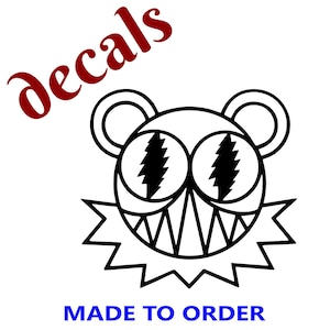 May include: Black and white decal featuring a stylized bear-like face with lightning bolt eyes and a jagged mouth. The word "decals" is in red script, and "MADE TO ORDER" is in blue block letters.