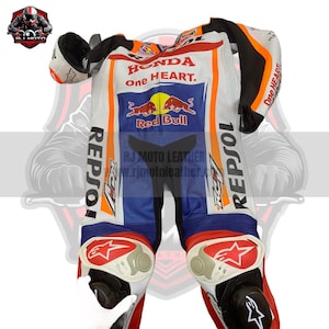 May include: A white, blue, and orange motorcycle racing suit with "HONDA one HEART" and logos. The suit features "REPSOL" branding and a star design on the knee pads. The suit is made of leather and has black accents.