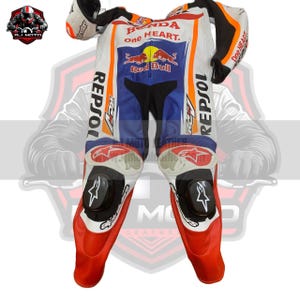 May include: A white, blue, and red motorcycle racing suit with "Honda, and "Repsol" logos. The suit has black knee sliders and orange accents. The suit is designed for protection and speed.