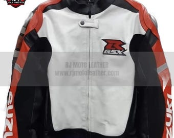 May include: A motorcycle leather jacket in black, white, and red. The jacket features a white front panel with a black collar and sleeves. The Suzuki GSX logo is on the chest. The text "RJ MOTO LEATHER" and a website address are printed on the jacket.