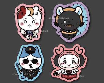 Puede incluir: Cuatro pegatinas de personajes de dibujos animados. Las pegatinas presentan un oso blanco con pelo rojo y marrón, un oso negro con una corona dorada, un gato azul con uniforme de policía y un personaje de pelo rosa. Las pegatinas tienen un contorno rosa, morado y azul.