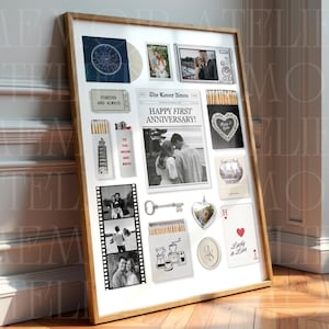 Op de afbeelding: Een ingelijste collage met een krantenknipsel getiteld The Lower News Happy First Anniversary, een filmstrip met drie foto's, een vintage sleutel, een hartvormige hanger, een speelkaart met een rood hart, luciferdoosjes en diverse kleine prints.