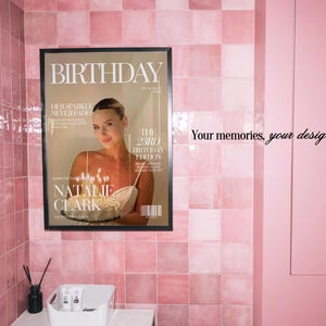 May include: A framed poster featuring a magazine cover design titled BIRTHDAY, displaying a person holding a cake with lit candles. The text includes HER SPARKLE NEVER FADES, THE 23RD BIRTHDAY EDITION, and NATALIE CLARK. The poster is mounted on a pink tiled wall.