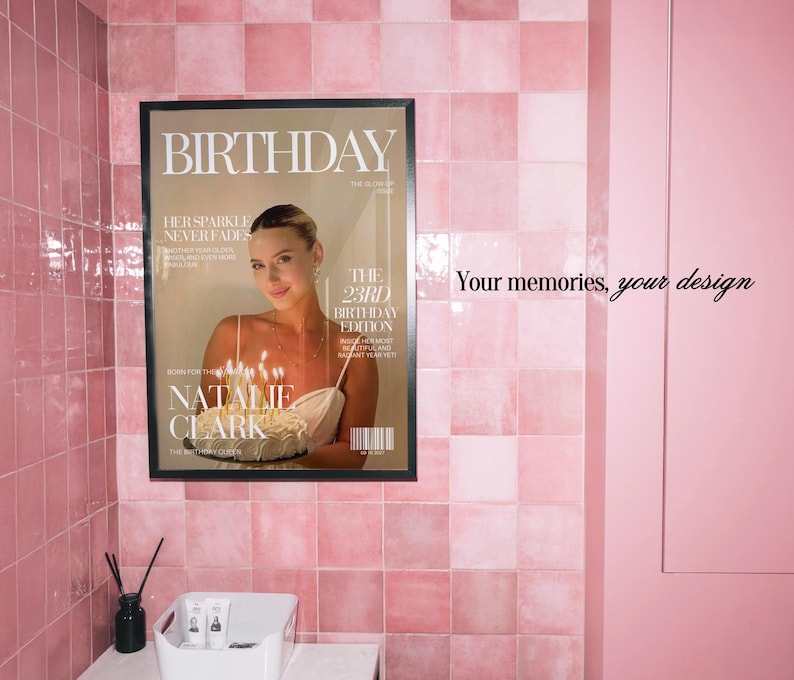 May include: A framed poster featuring a magazine cover design titled BIRTHDAY, displaying a person holding a cake with lit candles. The text includes HER SPARKLE NEVER FADES, THE 23RD BIRTHDAY EDITION, and NATALIE CLARK. The poster is mounted on a pink tiled wall.