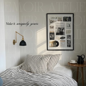 May include: A framed collage print featuring various black and white photographs, a newspaper clipping titled Happy Father's Day, and small memorabilia items. The print is displayed on a wall above a bed with black and white striped bedding.