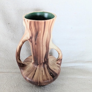 May include: A vintage vase with a unique design. The vase features a light brown and dark brown swirl pattern, with two handles and a green interior. The vase has a bulbous base and a flared top.