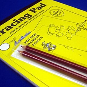 May include: A yellow tracing pad with the text "Tracing Pad" and "Create Your Own Transfer Patterns". The pad includes 50 sheets of paper. A pack of two red hot iron transfer pencils is included.