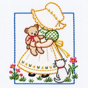 May include: A hand-embroidered design on white fabric featuring a figure in a yellow-trimmed bonnet and green checkered bodice holding a brown teddy bear with a red bow. A small white cat sits nearby, surrounded by pink flowers and green grass.