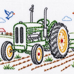 May include: An embroidery design featuring a green tractor with yellow wheels and black tires, positioned in a field with brown furrows. The background includes a small white farmhouse with a red roof, two blue birds, and two small blue clouds.
