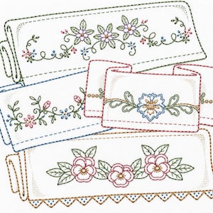 May include: A collection of four white rectangular fabric pieces featuring decorative machine embroidery. Each piece displays distinct floral patterns in shades of pink, blue, green, and brown, with stitched borders and scalloped edges.
