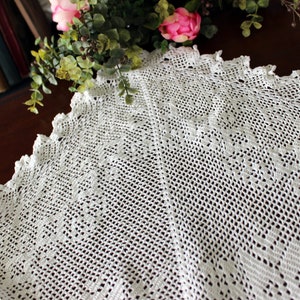 May include: White crocheted doily with a delicate lace pattern. The doily is circular and has a scalloped edge.