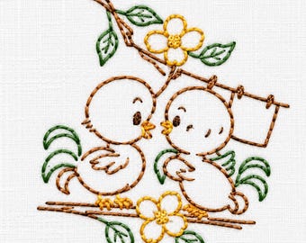 May include: An embroidery design on white fabric featuring two small birds perched on a branch with green leaves and yellow flowers. The birds are outlined in brown thread, and a rectangular frame is attached to the branch above the birds.