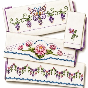 May include: Three rectangular white fabric pieces and one smaller vertical piece, each featuring colorful embroidery. Designs include a purple butterfly with floral vines, pink lotus flowers with blue wave borders, and hanging purple and pink floral garlands.