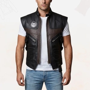 May include: Black and brown leather vest with a high collar and a zipper closure. The vest features a shield emblem on the chest and multiple pockets. The vest has a brown panel down the center and on the shoulders.