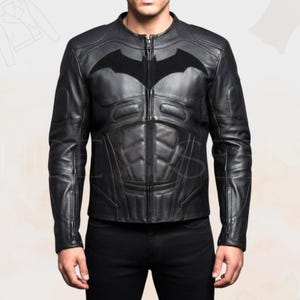 May include: Black leather jacket with a Batman logo on the chest. The jacket has a zip-up front, a round collar, and quilted detailing on the torso. The sleeves have zippers at the cuffs.