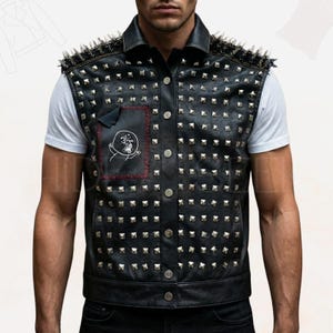 Puede incluir: Chaleco de cuero negro con tachuelas plateadas y detalles puntiagudos en los hombros. Cuenta con un parche con un gráfico de calavera. El chaleco tiene una parte delantera abotonada y un cuello. El modelo lleva una camiseta blanca debajo.