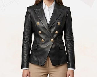Pode incluir: Um blazer de couro preto com abotoamento duplo e botões dourados. O blazer tem um design clássico com lapela entalhada e dois bolsos frontais. A modelo está vestindo uma camisa branca e calças bege.