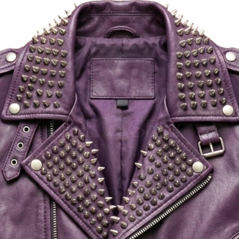 May include: Close-up of a purple leather jacket with silver metal cone studs on the collar and lapels. The jacket has a zipper closure, a small label, and silver button details. The jacket is a classic biker style.