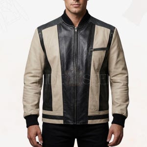 May include: A leather bomber jacket with a black collar, black and beige panels, and a black zipper. The jacket has black ribbed cuffs and a small zippered pocket on the chest. The jacket is made of leather.