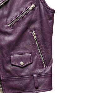 May include: Close-up of a purple leather jacket with silver zippers and a small pocket. The jacket has a classic biker style with a notched collar and a fitted silhouette. The text "HIDE" and "WER" is visible on the jacket.