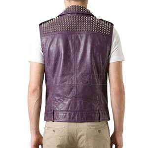 May include: Purple leather vest with silver metal studs on the shoulders and upper back. The vest has a classic design with a notched collar and a tailored fit. The back of the vest is visible, showing the stitching and the texture of the leather.