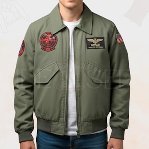 May include: Olive green bomber jacket with a zip-up front, two front pockets, and ribbed cuffs and hem. Features embroidered patches on the chest and sleeves, including a Top Gun logo and an American flag patch. The jacket has a classic collar.