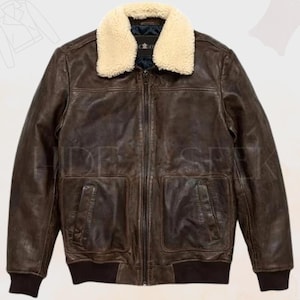 May include: A brown leather jacket featuring a cream-coloured shearling collar. The jacket has a zip-up front, two front pockets, and a ribbed hem. The jacket has the text "HIDE SEEK" on it.