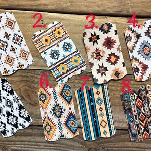 Puede incluir: Una colecci&oacute;n de ocho art&iacute;culos decorativos de polipiel con patrones geom&eacute;tricos del suroeste. Los dise&ntilde;os presentan varias combinaciones de colores, incluyendo blanco, negro, marr&oacute;n, azul y naranja, sobre una superficie de madera.