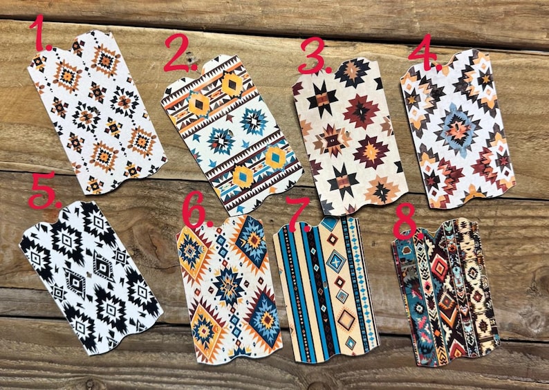 Puede incluir: Una colecci&oacute;n de ocho art&iacute;culos decorativos de polipiel con patrones geom&eacute;tricos del suroeste. Los dise&ntilde;os presentan varias combinaciones de colores, incluyendo blanco, negro, marr&oacute;n, azul y naranja, sobre una superficie de madera.