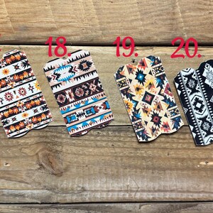 Puede incluir: Cuatro llaveros decorativos con patrones del suroeste. Los llaveros presentan dise&ntilde;os geom&eacute;tricos en varios colores, incluyendo naranja, blanco, negro y turquesa, sobre un fondo de madera.