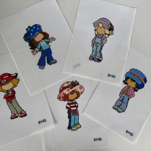 Puede incluir: Cinco imágenes bordadas de personajes de dibujos animados sobre tela blanca. Cada personaje lleva un sombrero y un atuendo de varios colores, incluyendo azul, rojo y rosa. Los personajes están en diferentes poses. Las letras "BMG" están en la esquina inferior derecha de cada imagen.