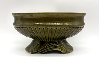 May include: A green ceramic planter with a fluted design and a decorative base. The planter is oval shaped and has a wide rim.