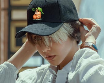 May include: A black baseball cap with a brown cap wearing a green cap and the text "That's Cap" on the front.