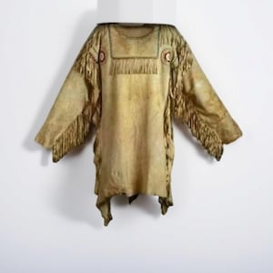 Peut inclure: Une tunique à franges de couleur beige avec des manches longues. Le vêtement présente des éléments décoratifs autour de l'encolure et des épaules, et est probablement fait de cuir ou d'une matière similaire. La tunique est présentée sur fond blanc.