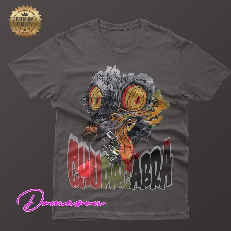 May include: Dark gray t-shirt featuring a watercolor illustration of a Chupacabra with large yellow eyes and sharp teeth. The word "CHUPACABRA" is printed in a distressed font below the creature.