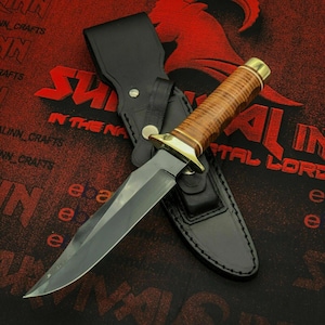 May include: A large, fixed-blade knife with a brown leather handle and a black sheath. The blade is silver and the handle has brass accents. The sheath is black leather with a snap closure. The knife is on a red background with white text.