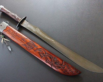 May include: A detailed image of a sword with a wooden handle and sheath. The blade is silver, and the handle is brown with intricate carvings. The sheath is also brown, with carved designs and text. A decorative feather hangs from the sheath.