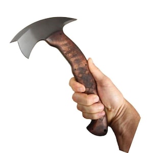 以下が含まれることがあります： 湾曲した刃と木製の柄が付いた、濃い色の刃のハチェット。 柄は、装飾的な彫刻が施された、質感のある茶色の仕上げです。 ハチェットは、切断と切断のために設計されています。