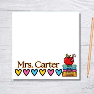 May include: A white notepad with the text "Mrs. Carter" in brown and gold. Below the text are six colorful hearts. A cartoon apple with a worm sits atop a stack of books labeled with subjects.