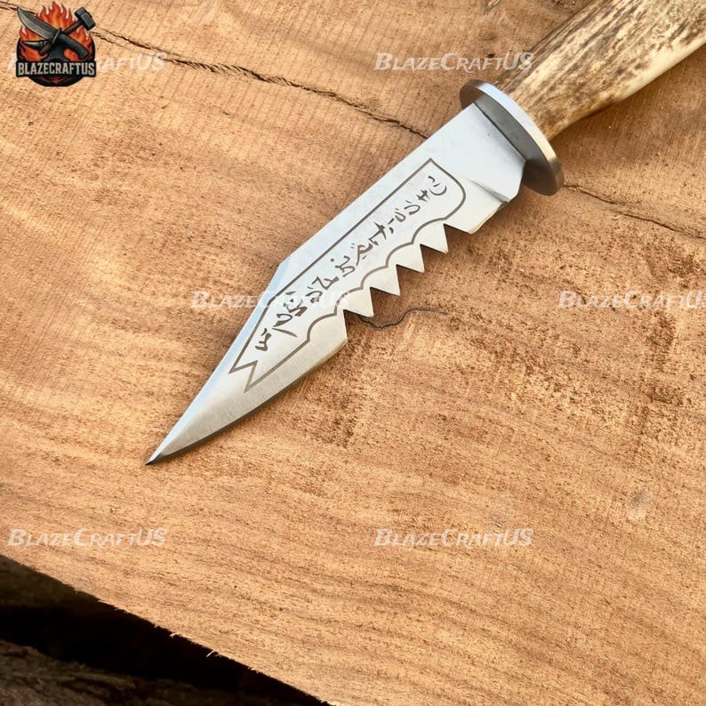 May include: A handcrafted knife with a serrated blade and a light-colored antler handle. The silver blade has etched text and a decorative edge. The knife is displayed on a wooden surface.