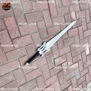 May include: A silver-colored sword with a black handle and a decorative hilt. The blade is long and pointed, and the handle is wrapped in black material. The sword is lying on a brick surface.