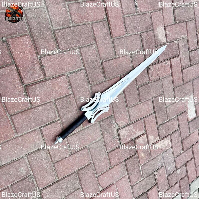 May include: A silver-colored sword with a black handle and a decorative hilt. The blade is long and pointed, and the handle is wrapped in black material. The sword is lying on a brick surface.