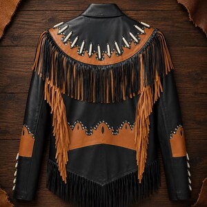 May include: A black leather jacket featuring tan leather accents, long black and tan fringe detailing, and a decorative yoke adorned with white cylindrical beads and silver-toned metal studs. The jacket includes a pointed collar and long sleeves.