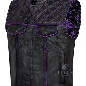 May include: Black leather vest with purple stitching and accents. Features a quilted shoulder design and two front pockets. The vest has a stand-up collar and a paisley pattern on the shoulder. The Bull's Leather Hub logo is visible.
