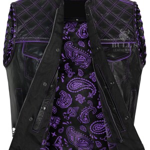 May include: Black leather vest with purple stitching and a paisley interior. The vest features a quilted design on the shoulders and pockets. The vest has a zipper closure and snap buttons. The Bull's Leather Hub logo is visible in the upper right corner.