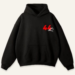 May include: Black hoodie with a front kangaroo pocket and a hood. The number "44" is printed in red on the upper left chest, with a white signature below it. The hoodie is made of a soft material.