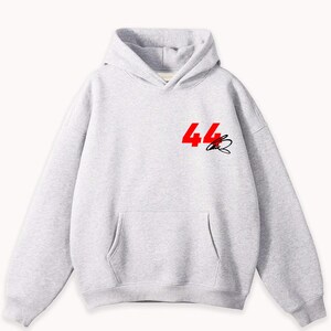 May include: A light gray hoodie with a front pocket and hood. The number "44" in red and a black signature are printed on the upper left chest area. The hoodie is made of a soft material.